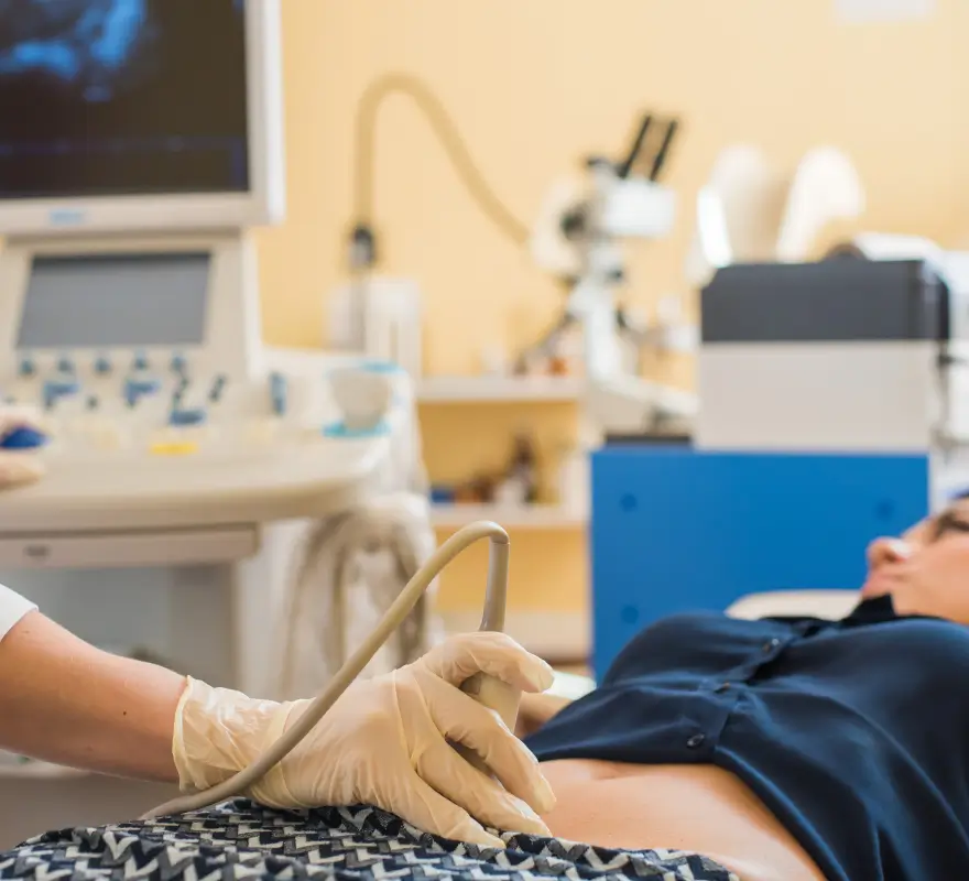 Healthcare provider performing an ultrasound on a pregnant woman's abdomen during a non-invasive prenatal paternity test