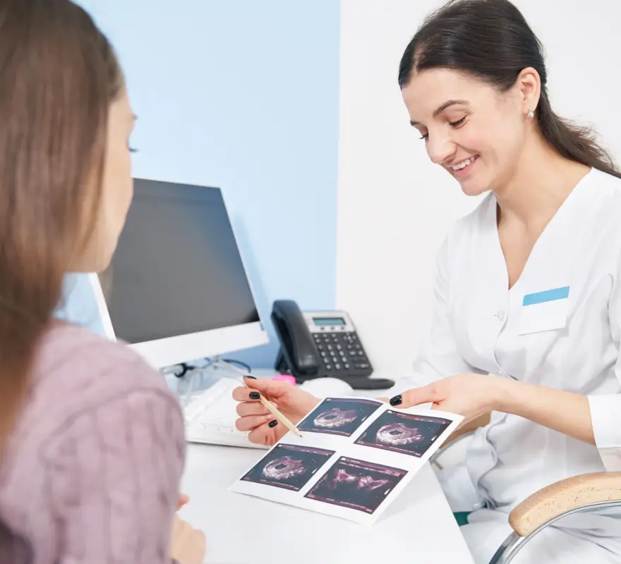 Pregnant woman reviewing ultrasound images with a female healthcare provider during a prenatal paternity testing consultation
