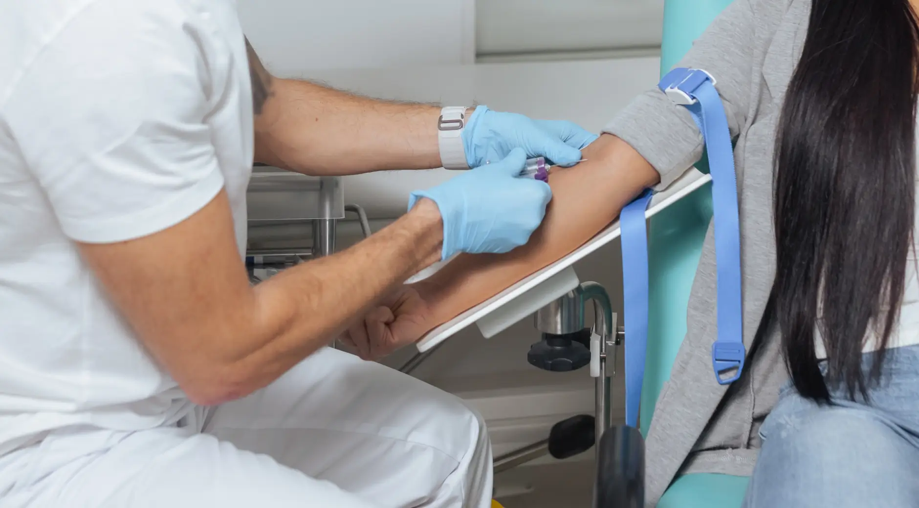 Male healthcare provider drawing blood from a woman's arm for prenatal paternity testing sample collection